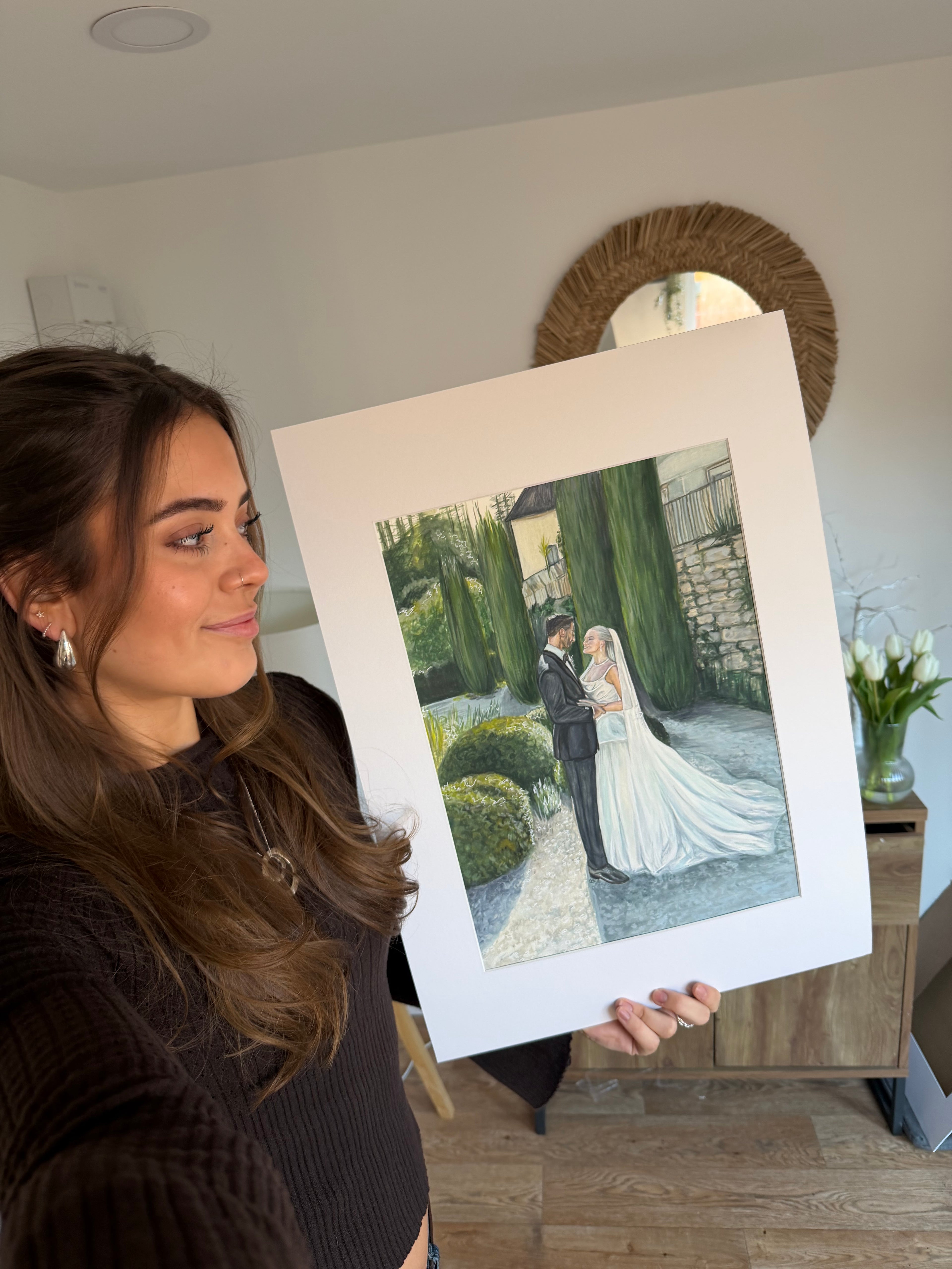 Dizzign wedding artist Izzie Turner holding a finished couple portrait
