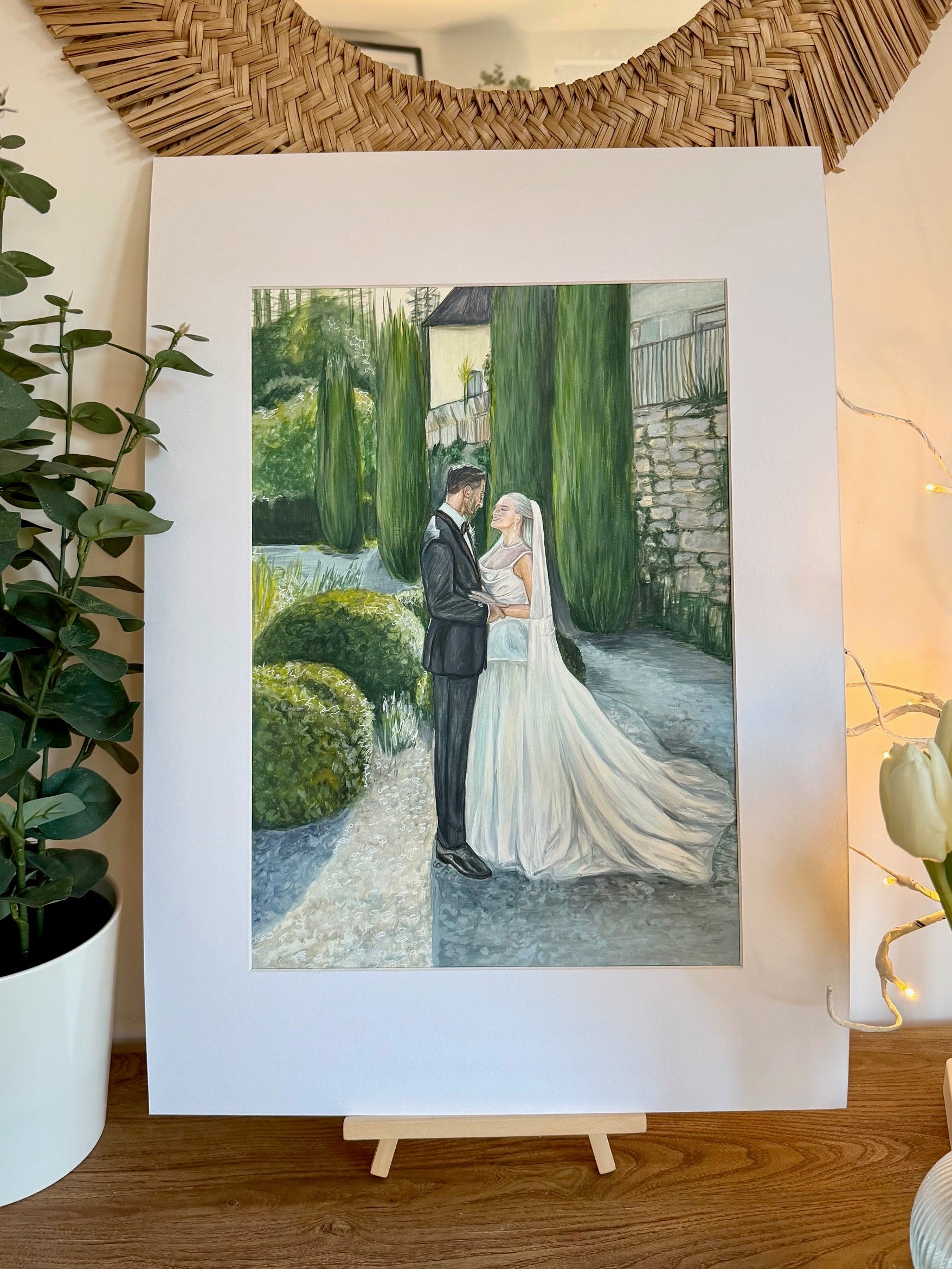 Finished colour wedding portrait of a bride and groom at a garden venue, displayed on an easel